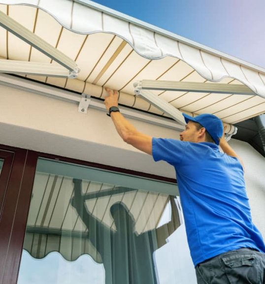 Worker fixing white awning — Door & Window Furnishings in the Northern Rivers